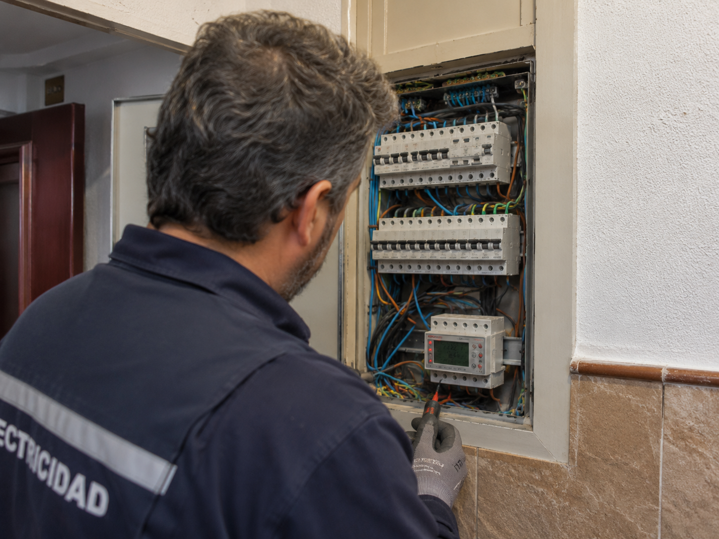 Electricista revisando un cuadro eléctrico abierto en un edificio de comunidad de vecinos en Sevilla